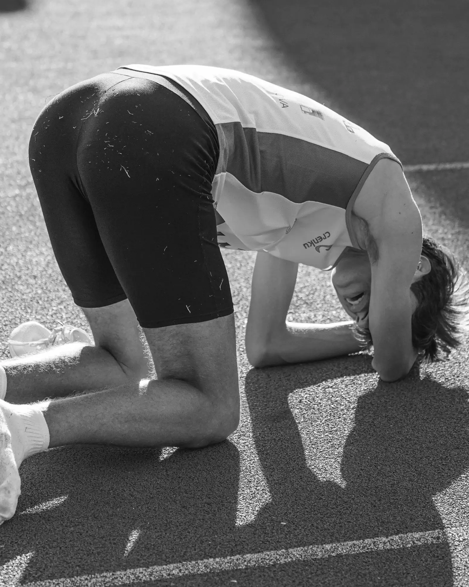 Un atleta exhausto, de rodillas en la pista